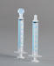 Two plastic oral syringes, one with a bulb and the other with a simple tip, sit on a gray background. The syringes are graduated in milliliters (ml) from 0.5 ml to 3 ml.