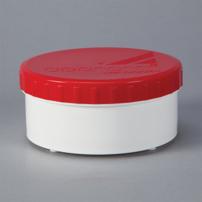 A small, cylindrical white container with a red lid sits on a gray background.