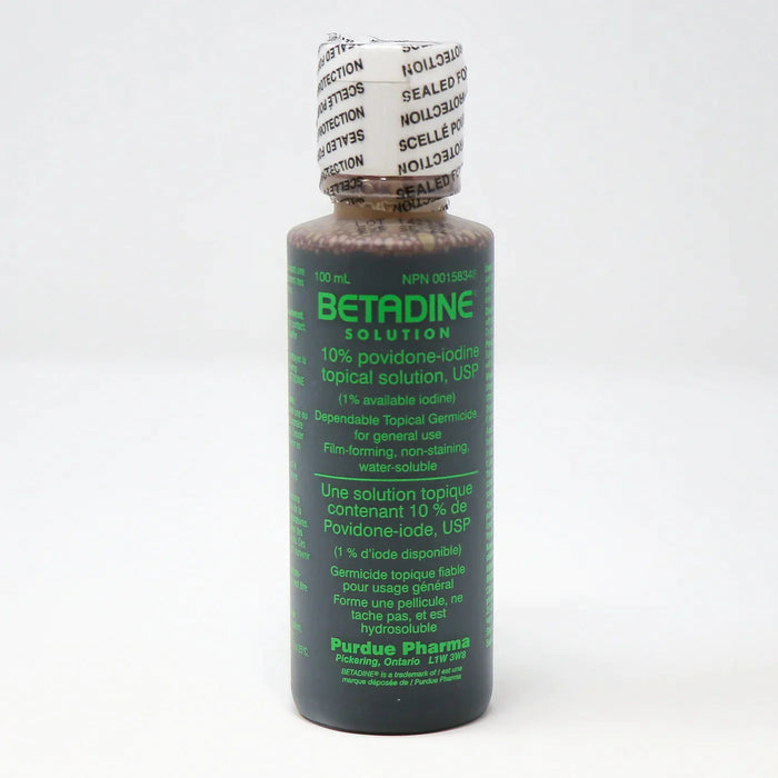 A dark-brown bottle of Betadine solution sits on a white surface. The label indicates it's a 10% povidone-iodine topical solution, a germicide for general use. The bottle is sealed.