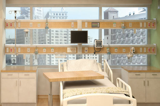 A hospital bed sits in a room. It is positioned beneath a window showcasing a city view and multiple medical control panels mounted on the wall above. Cabinets flank the bed on either side.