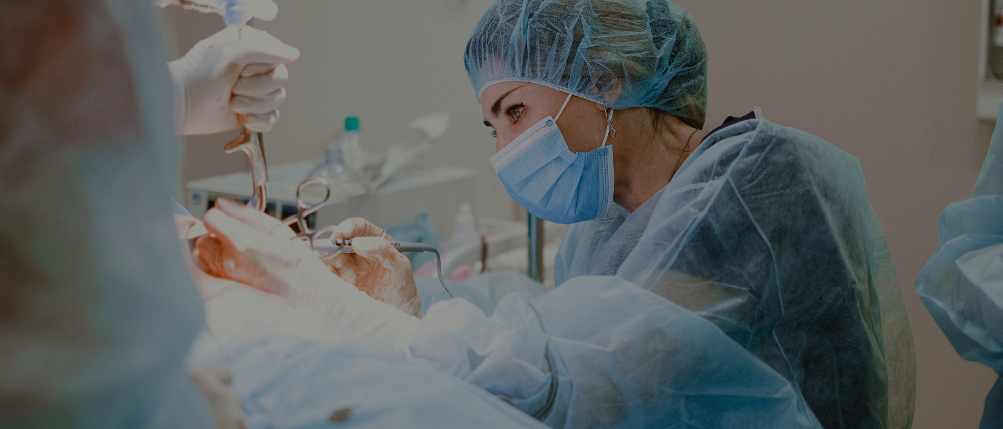 A surgeon performs a procedure using surgical instruments, in an operating room.