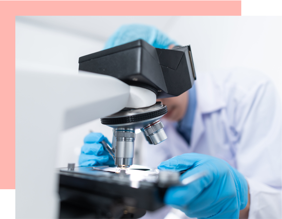 A scientist operates a microscope, adjusting its focus in a laboratory setting.