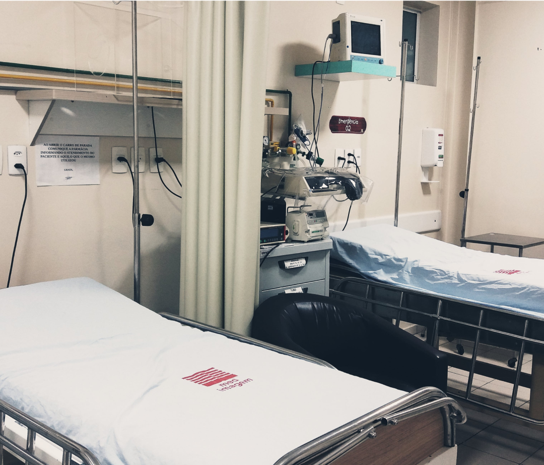 Hospital beds sit empty in a room; medical equipment and oxygen are nearby. A sign reads: "When opening the cabinet, inform the pharmacy of the patient's care and what they used."