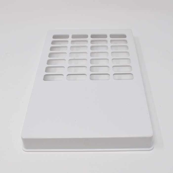 A white rectangular plate with numerous rectangular cutouts sits on a white surface.