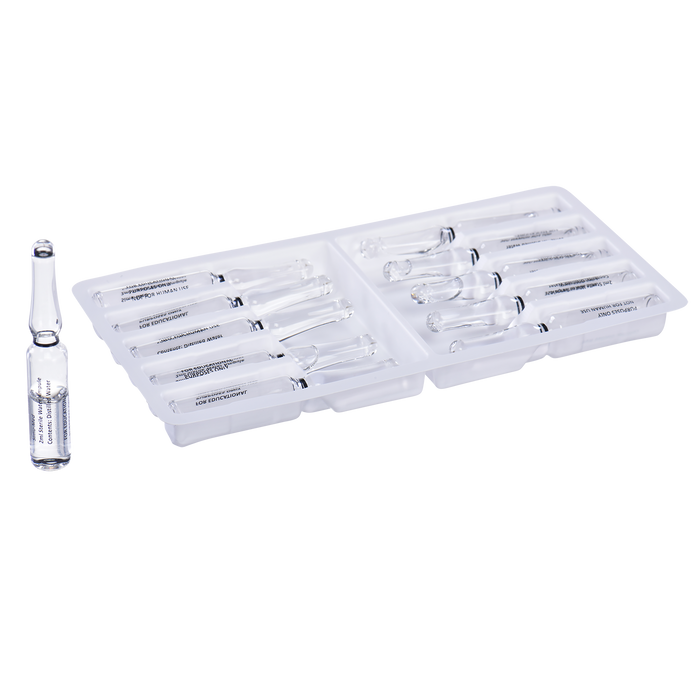 A glass ampoule containing sterile water rests near a plastic tray holding similar ampoules. The tray is partially filled; ampoules are nestled in the compartments.