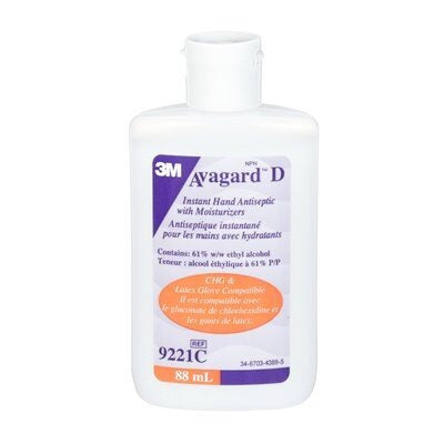 A 3M Avagard D hand antiseptic bottle sits on a surface. It contains 61% ethyl alcohol and moisturizers. The bottle is labeled with product information in English and French.