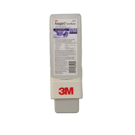 A 3M hand sanitizer dispenser sits upright, dispensing lotion. The dispenser is packaged in a white and grey plastic casing with a small purple label, showing instructions and a barcode.