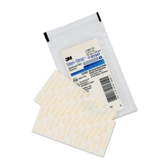 Two Steri-Strip reinforced skin closures rest outside their package. The package is transparent plastic. The closures are rectangular, off-white with a pattern, and adhesive.