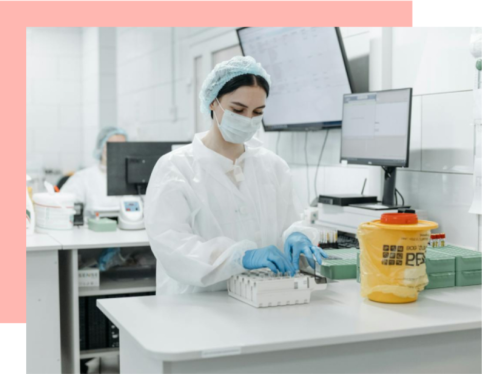 A lab technician handles test tubes while wearing PPE in a sterile laboratory setting.