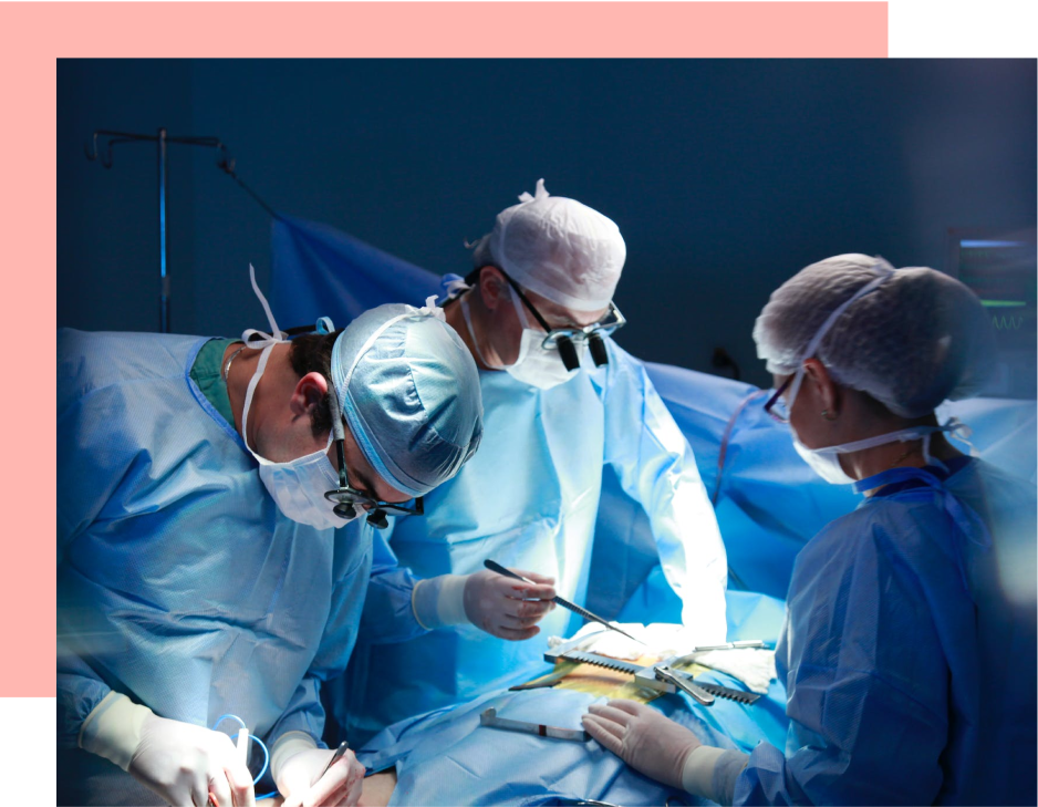 Three surgeons perform surgery, using surgical tools on a patient, in a dimly lit operating room.