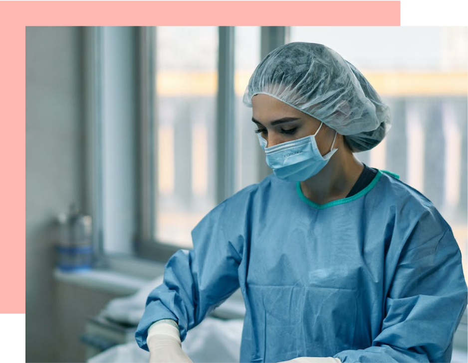 A surgeon prepares, donning gloves in a hospital operating room.