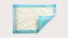 A rectangular absorbent pad, partially folded, displays a light-colored absorbent center and a light blue border; it rests on a plain white background.