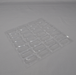 A clear plastic tray with numerous small, rectangular depressions lies on a light gray surface.
