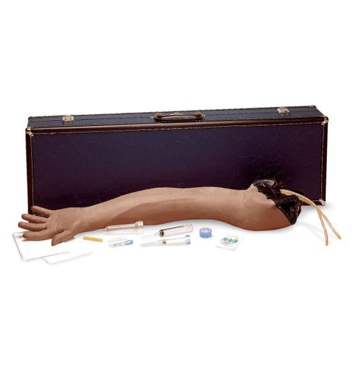 A realistic arm model lies near a carrying case, accompanied by syringes and other medical supplies. It is likely used for medical training.