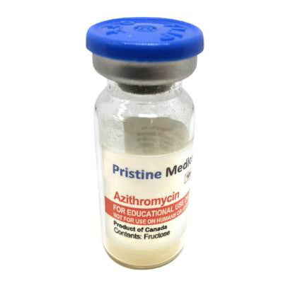 A small, clear glass vial containing a light beige powder sits upright. The vial is capped with a blue lid and features a label indicating it's Azithromycin, for educational use only, produced in Canada and containing fructose.