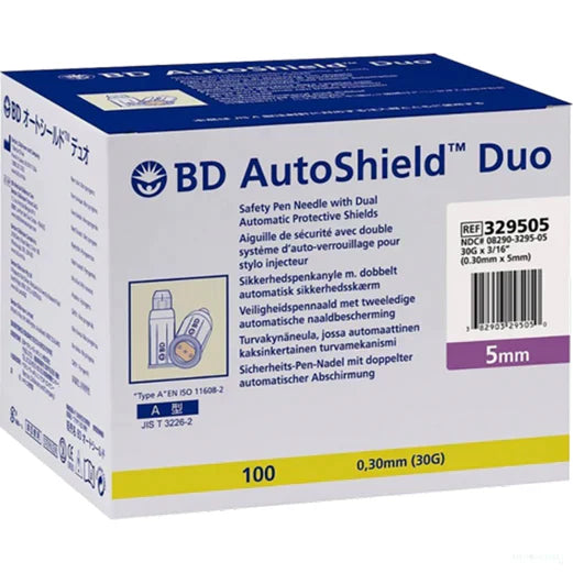 A box of BD AutoShield Duo safety pen needles with dual automatic protective shields sits on a surface. The box contains 100 needles, 0.30mm (30G) x 5mm in size. REF 329505, NDC# 08290-3295-05.