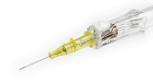 A yellow intravenous cannula rests on a gray surface; its needle is pointed towards the lower left.