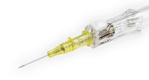 A yellow intravenous cannula rests on a gray surface; its needle is pointed towards the lower left.