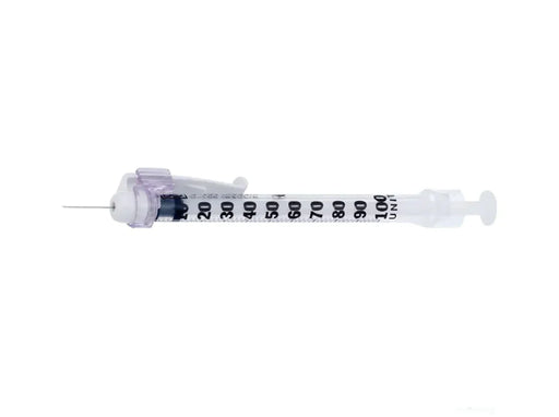 A syringe lies horizontally on a plain white background. The syringe is transparent with black markings along its barrel.