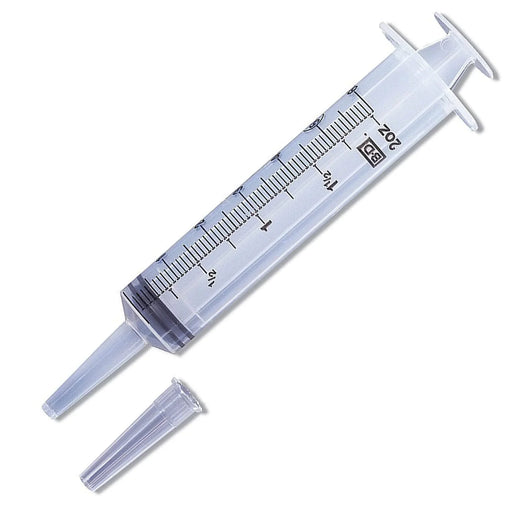 A clear plastic syringe, measuring 20 cc, lies on a white background with its tip and cap detached. The markings indicate measurements in milliliters.