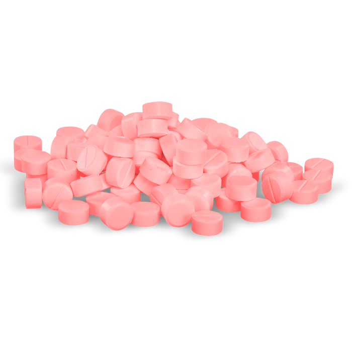 Many pink pills are piled haphazardly against a black background.
