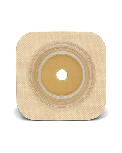 A beige, square ostomy wafer with a central, smaller, tan, circular adhesive opening sits on a white background.
