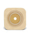 A beige, square ostomy wafer with a central, smaller, tan, circular adhesive opening sits on a white background.