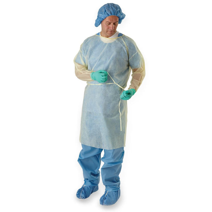 A pale-yellow disposable gown is being tied by a person wearing teal gloves and a blue surgical cap against a white background.