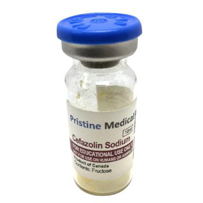 A small glass vial contains a beige powder. It's labeled "Cefazolin Sodium," for educational use only, and lists fructose as a content. The vial has a blue cap.