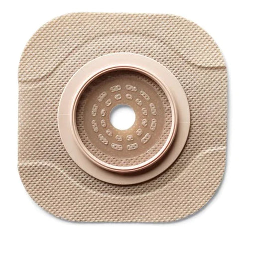 A beige, square ostomy wafer with a central, ringed aperture sits on a white background.