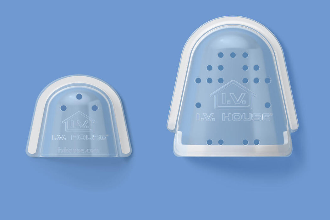 Two light-blue, perforated, semi-circular plastic finger cots sit against a solid blue background. The larger cot is positioned behind the smaller one.