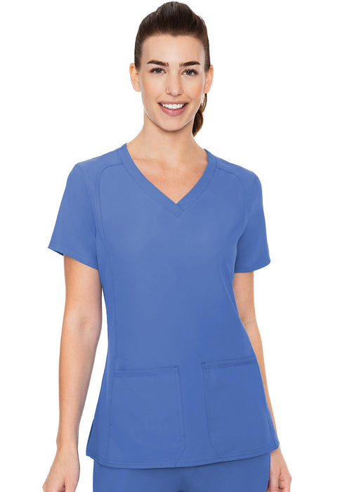 A woman models a royal blue V-neck scrub top with short sleeves, standing against a plain white background.