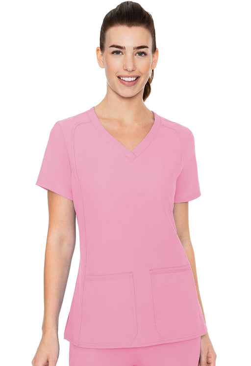 A pink v-neck scrub top is being modeled by a woman against a white background. The top has short sleeves and appears to be made of a lightweight fabric.