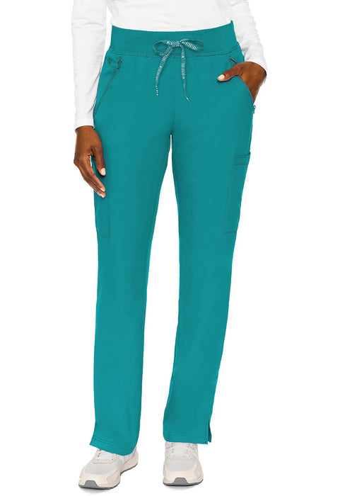 Teal scrub pants are modeled against a white background. The pants are straight-legged and have pockets. A person's hands are in the pockets.