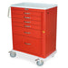 A red medical cart with six drawers sits on wheels. It features a handle and a light-colored top.