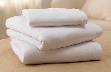 A neatly folded stack of white sheets sits on a light beige surface. The sheets appear soft and are likely made of cotton or a similar material.