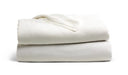 Two off-white blankets are stacked neatly on a plain white background. A small portion of a tag or label is visible on top.