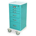 A teal medical cart with six drawers sits on four small wheels. It is likely used for storing and transporting medical supplies.