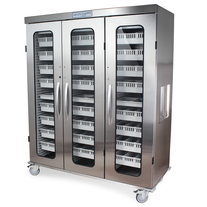 A stainless steel cabinet with three glass doors sits on wheels. Inside are numerous small, light-colored drawers. The cabinet is labeled "MEDSTORMAX".