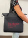 A black McMaster University Nursing tote bag is being carried by a person. McMaster University NURSING is printed on the bag.