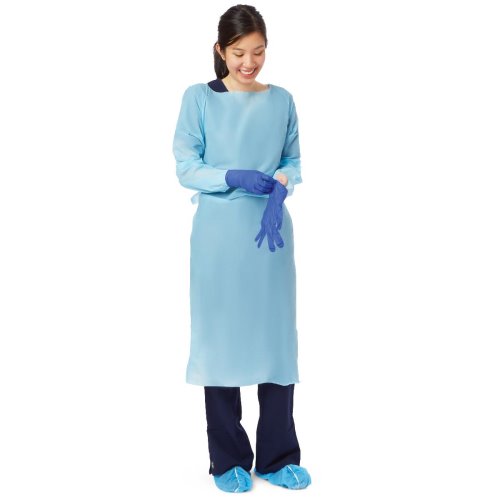 A woman in a light blue surgical gown puts on blue gloves against a white background.