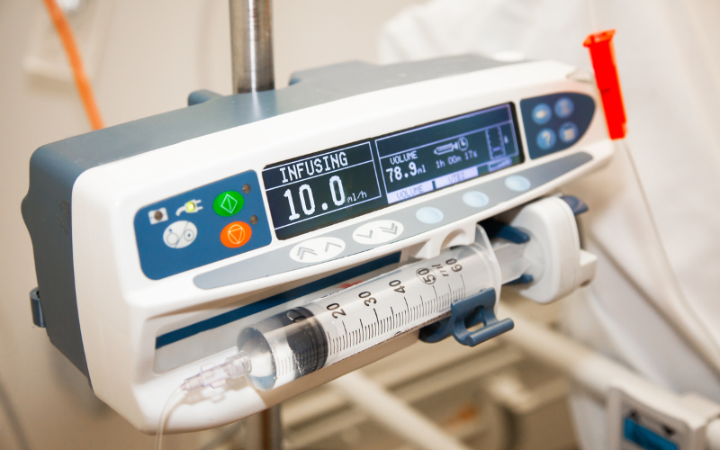 An intravenous infusion pump infuses fluid at 10.0 ml/h in a hospital room. The display shows a volume of 78.9 ml remaining.