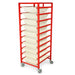 A red metal cart holds ten off-white trays; it sits on wheels, likely for mobility.