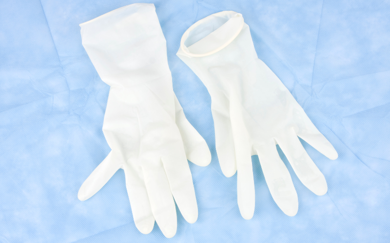 Two white latex gloves lie flat on a light blue surgical drape.