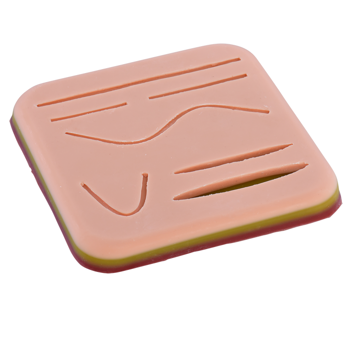 A pale pink, layered practice skin displays various incised lines and curves for suture training.