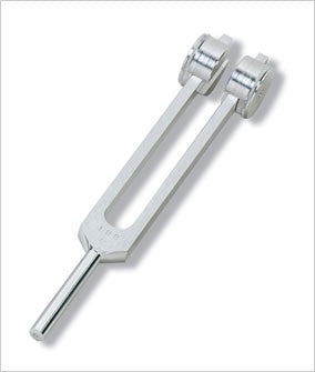 A metal tuning fork rests on a plain white background. The number "128 HZ" is visible on its stem.