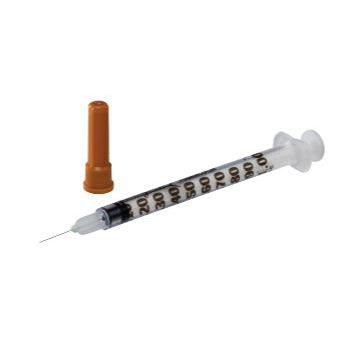 A disposable syringe lies on a plain white background; next to it is its protective cap.