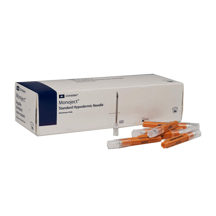 A box of Monoject Standard Hypodermic Needles with aluminum hubs sits beside several needles. The needles are orange and are displayed on a white surface.