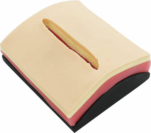 A layered, skin-toned pad with a simulated incision rests on a black base.