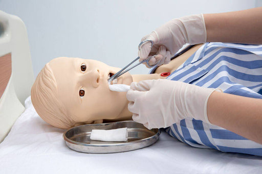 A medical mannequin’s mouth is being worked on with forceps and gauze by gloved hands. The procedure takes place on a medical table.